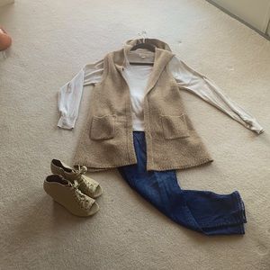 Sleeveless cardigan with pockets and a hood.